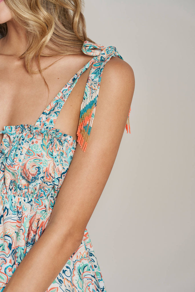 A close up look on the over-the-shoulder ties with handmade beads fringes of the Shine Short Dress.