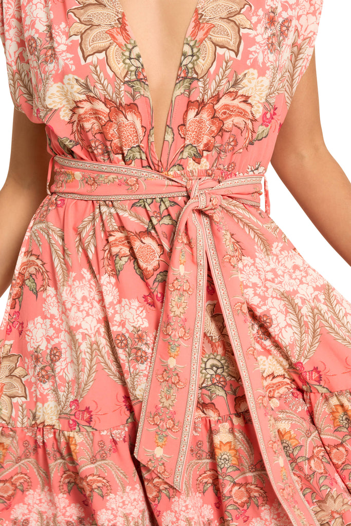 A close up image of a model wearing the Spirit of Love Short Dress, with a sexy deep V line in the front, sleeveless, with a removable belt, with a vibrant floral pattern.